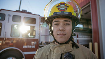 Firefighter with helmet standing in front of a fire truck.