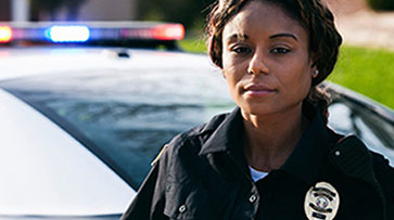 Uniformed police officer standing in front of a police car.