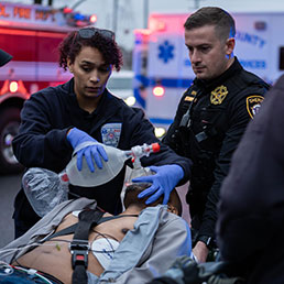 First responders using a bag valve mask and an AED to assist an injured person.