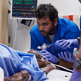 A healthcare professional using a bag valve mask to provide manual resuscitation for a patient.