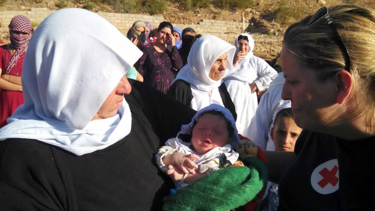 Women gather around an infant child held in the arms of her mother.