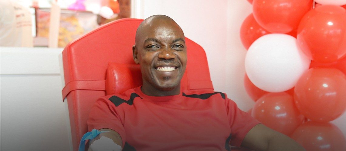 man sitting in blood donation chair with big smile